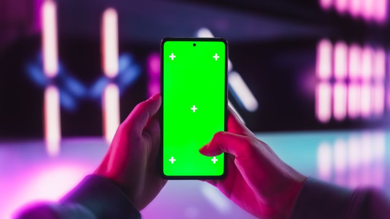 POV Person Scrolling Through Apps on Smartphone with Green Screen Chromakey Mock Up Display in a Futuristic Neon Room. Picture Template with Isolated Placeholder for Digital Marketing Campaigns